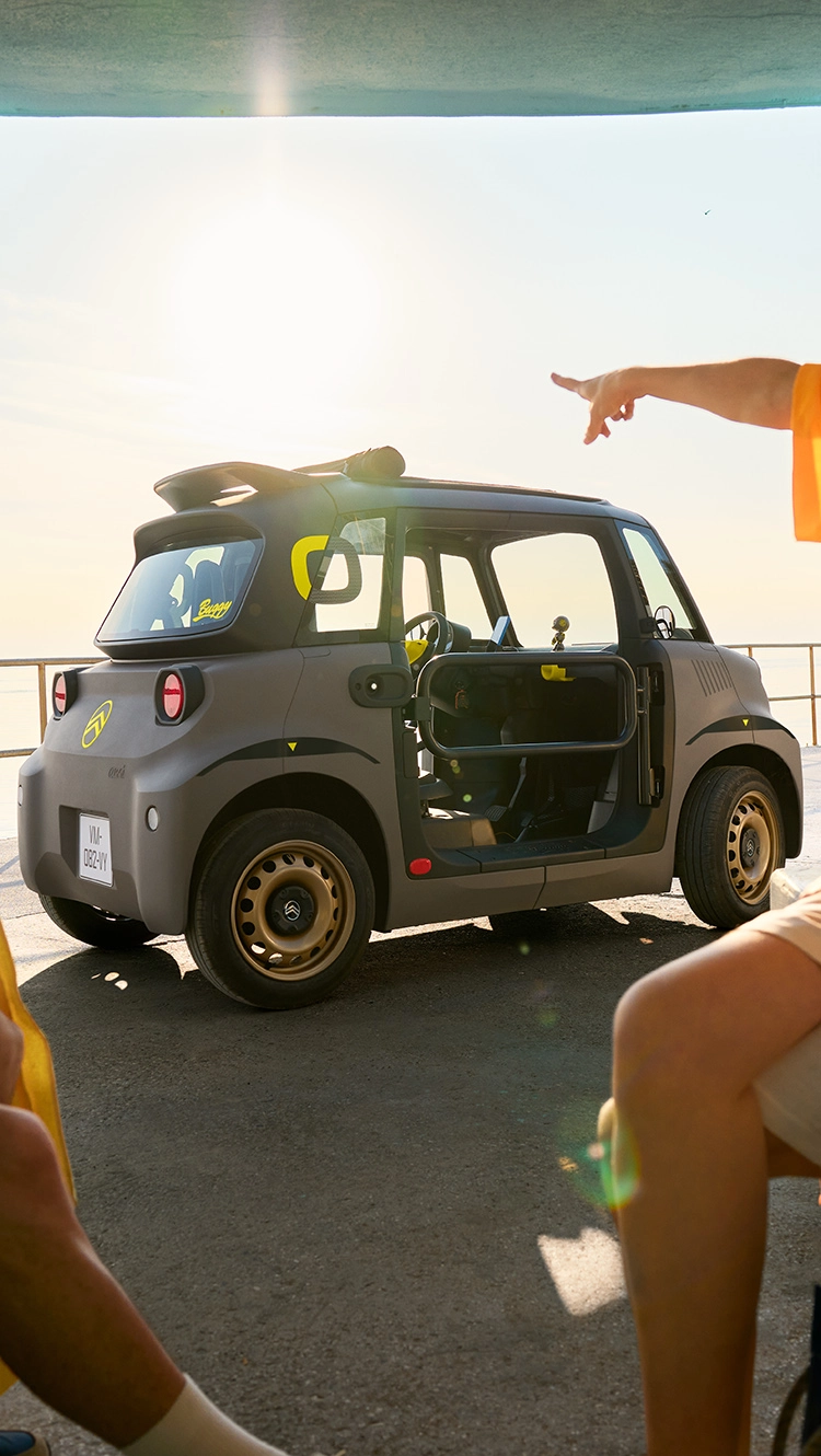 Vue latérale d'une plage et d’une Citroën Ami mettant en avant un design électrique compact, sûr et fiable, offrant une liberté estivale innovante.